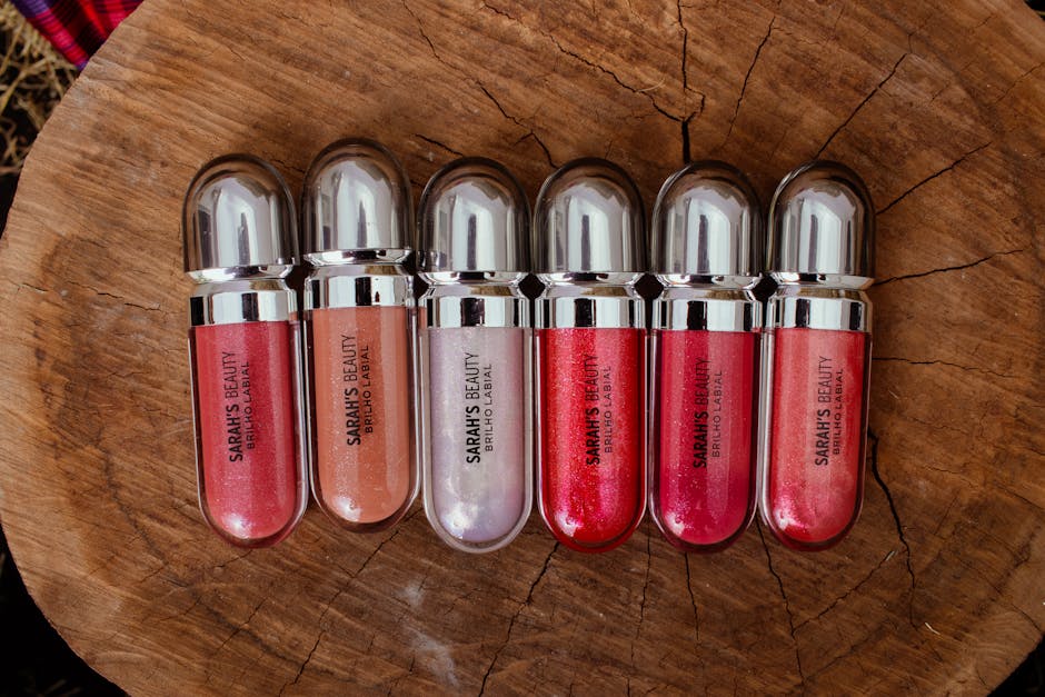 Explore the variety of vibrant lip glosses displayed on a natural wood surface for unique beauty inspiration.